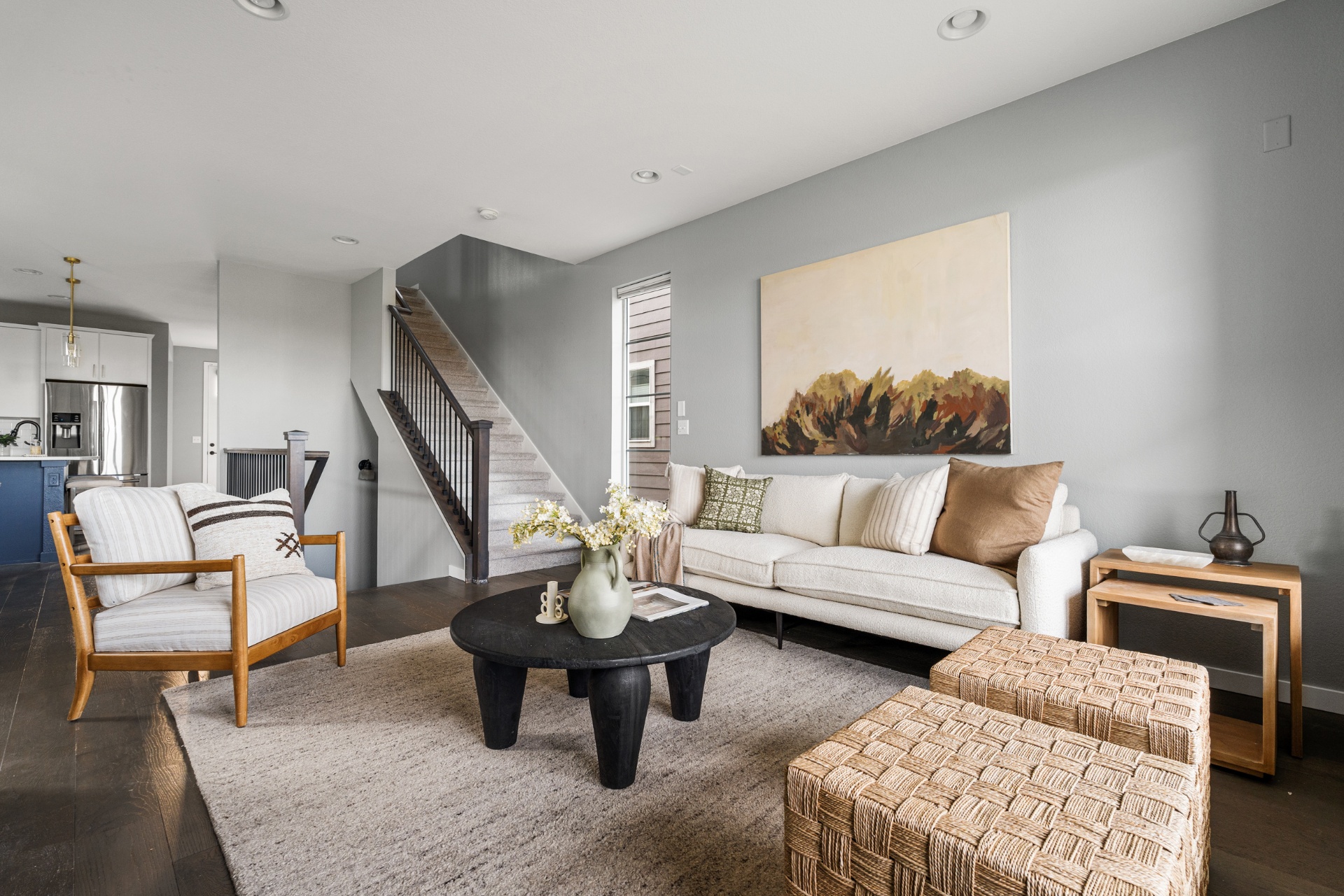 Staged living room with sofa, accent chair, and stair view